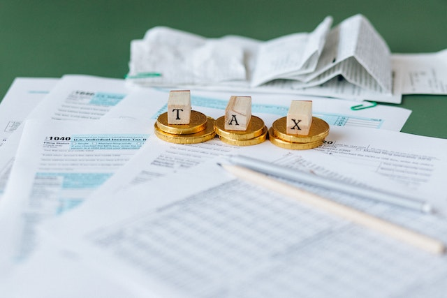 A-Stack-Of-Tax-Documents-With-Wooden-Blocks-That-Spell-Tax-Laid-On-Top