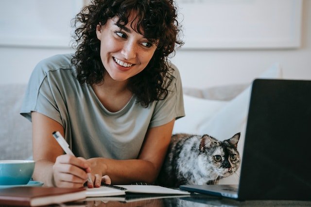 A-Person-Writing-In-A-Notebook-With-A-Cat-Beside-Them