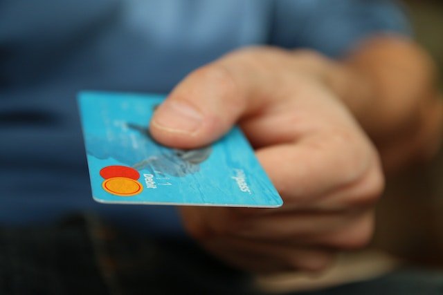 Hand Reaching Out Holding A Blue Credit Card