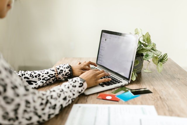 Person Making An Online Payment On A Laptop With Credit Cards Next To Them